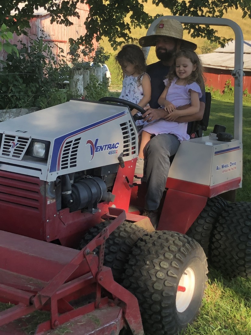 Photo of father and daughters sitting on Compact Tractor